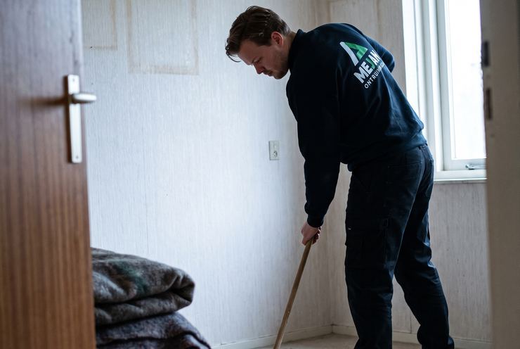 Medewerker veegt de lege kamer na als laatste stap voor de oplevering