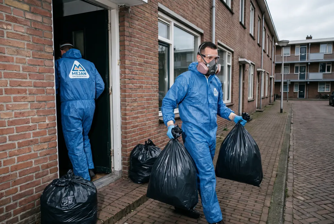 Medewerkers in beschermende kleding dragen afvalzakken uit een sterk vervuilde woning