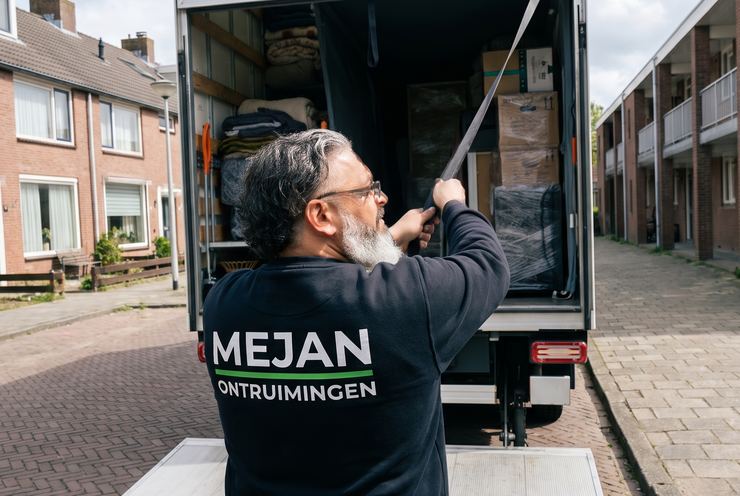 Medewerker sluit de volgeladen bakwagen aan het einde van de klus